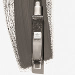 Clear spray bottle with label on a textured gray background